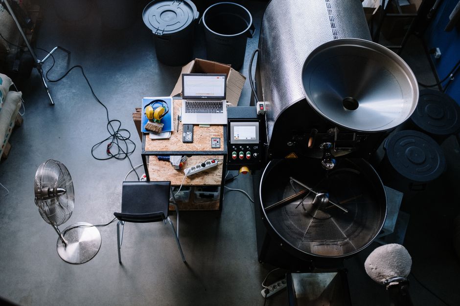 warm rustic coffee roastery interior with drum roaster, morning light