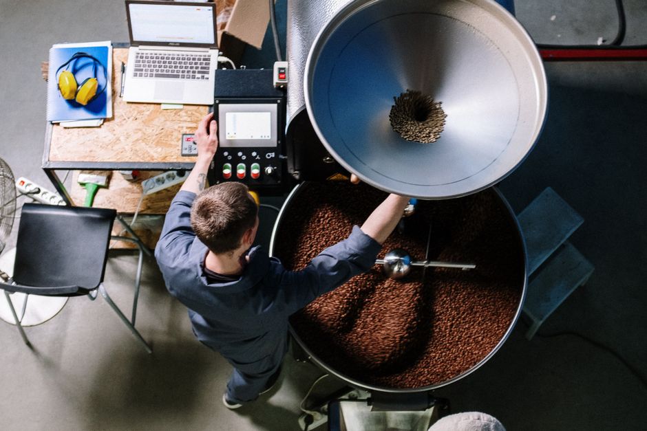 warm rustic coffee roastery interior with drum roaster, morning light